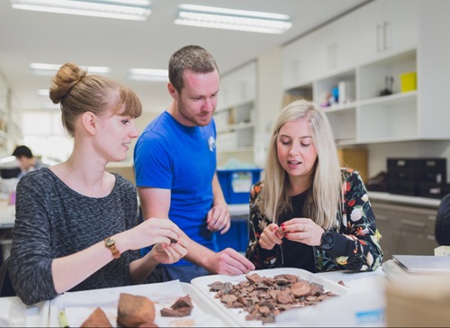 Three students look at rocks