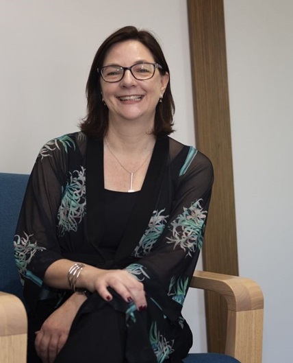 Ariadne Vromen. A woman wearing glasses, seated on a blue chair, smiling and appearing relaxed and friendly.