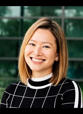 Nicole Curato, a woman with short hair wearing a stylish black and white sweater, with a broad smile exuding confidence.