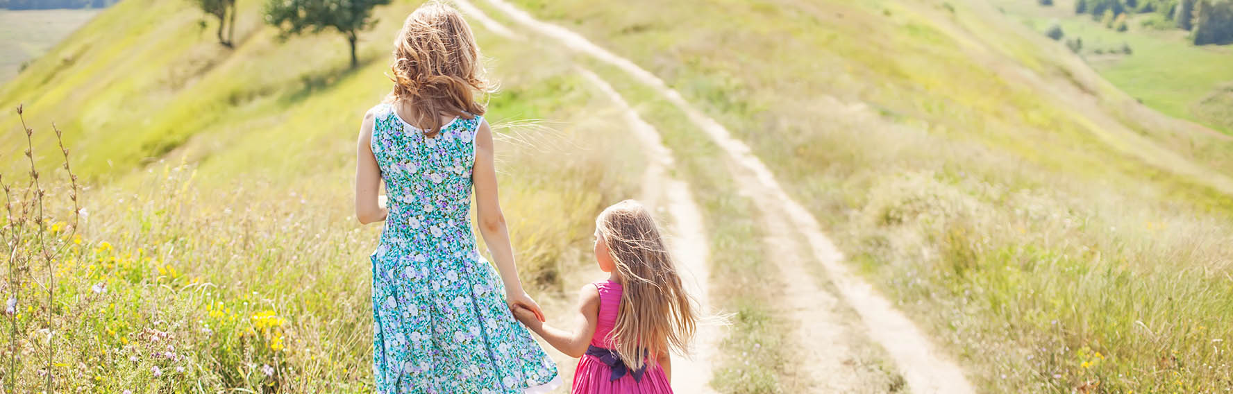 Mother and daughter holding hands walking in a field together
