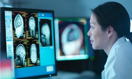 A person looking at a screen with scans of a brain