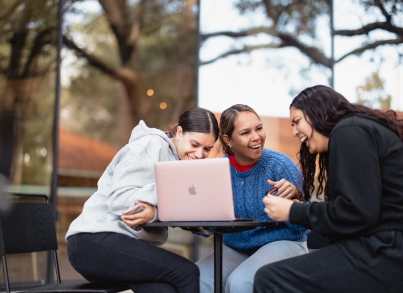 Three students looking at laptop